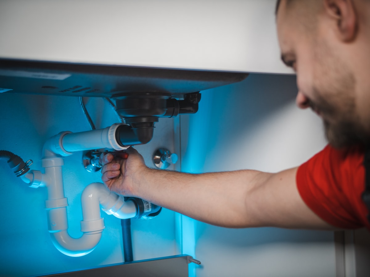 Plumber clearing a clogged drain under a sink